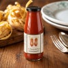 パスタと食器を背景に木製テーブルに置いた、Le Masserie del Ducaのトマトパッサータ